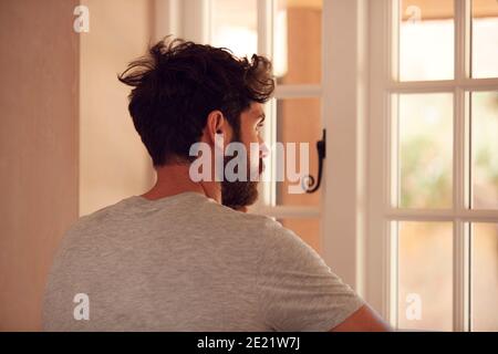 Rear View Of Builder Looking Out Of Window At New Build Property Stock Photo