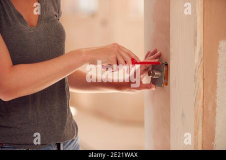Close Up Of Female Electrician Fitting Light Switch At New Build Property Stock Photo