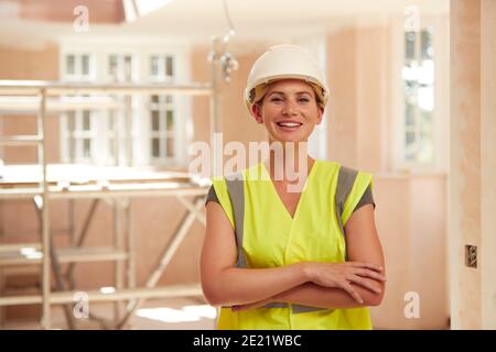 Portrait Of Smiling Female Builder Wearing Hard Hat Working In New Build Property Stock Photo
