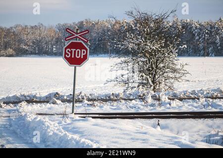 STOP road sign, at a railway crossing, in a winter snowy landscape Stock Photo