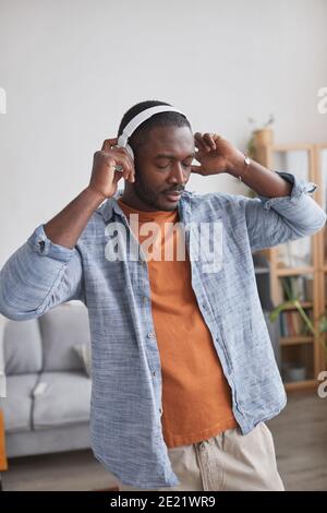 Medium portrait shot of handsome African American man wearing casual outfit enjoying music in headphones Stock Photo