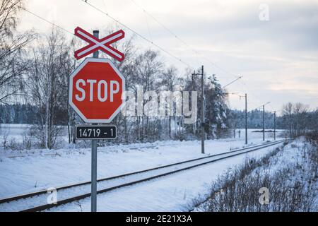 STOP road sign, at a railway crossing, in a winter snowy landscape Stock Photo