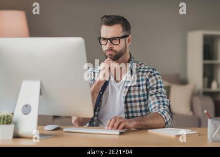 Photo of young man serious confident serious look think browse read computer distance work desk indoors Stock Photo