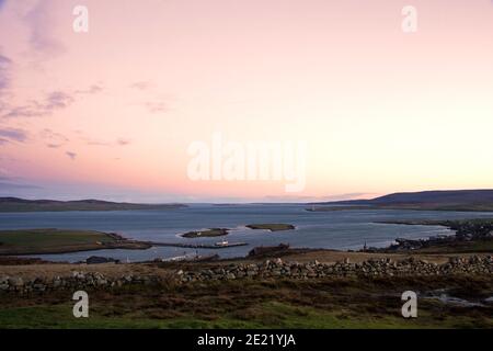 View from top of hill of two small islands and harbour on Orkney islands with clear sky Stock Photo