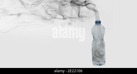 Black Smoke out of plastic bottle with copy space showing recycling, pollution and benefits of reusable zero waste materials. Stock Photo