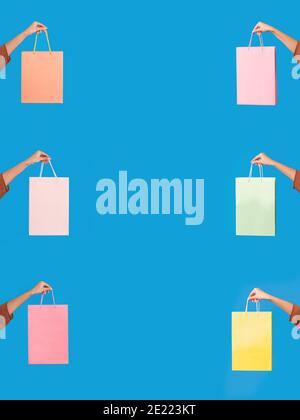 Female Hands Holding Shopping Bags Over Blue Studio Background Stock Photo