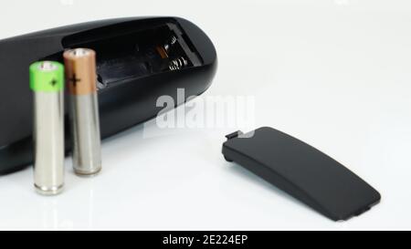 Black TV remote control with AAA alkaline batteries on a white background. Battery replacement, spare parts. Close up of an empty battery compartment Stock Photo