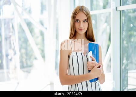 Confident smiling businesswoman with clipboard in a bright modern office with copy space. business professionals Stock Photo