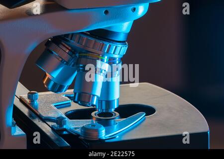 Microscope in laboratory at night in blue light. Microbiology and research concept. Stock Photo