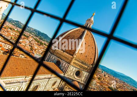 Stunning rooftop view of the dome of Santa Maria del Fiore Cathedral with the cupola on top, and overlooking Florence through a window grate in the... Stock Photo