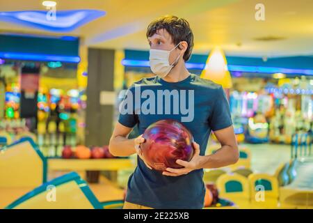 Man playing bowling with medical masks during COVID-19 coronavirus in bowling club Stock Photo