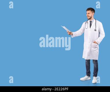 Smiling Male Doctor Recommending Medical Treatment Standing Over Blue Background Stock Photo