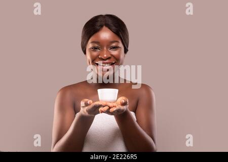 Skin Nourishing. Attractive Black Woman Holding Jar With Moisturising Cream In Hands Stock Photo