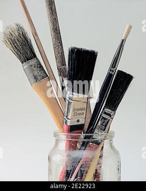 Photo illustration Artist brushes in a jar against a simple plain background Stock Photo
