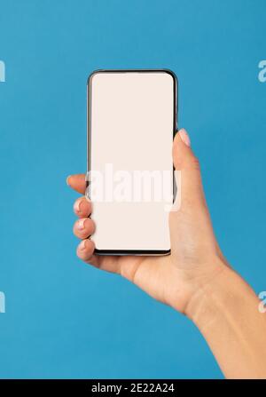Female Hand Holding Phone With White Screen Over Blue Background Stock Photo