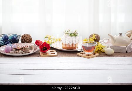 Easter cake, eggs, flowers and decor details on the table. Family holiday concept of Easter and table setting. Stock Photo
