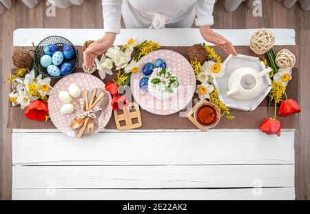 Festive Easter table with homemade Easter cake, tea, flowers and decor details copy space. Family celebration concept. Stock Photo