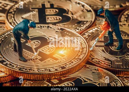 macro miner figurines working on group of bitcoins. virtual cryptocurrency mining concept Stock Photo
