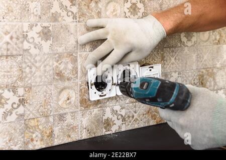 An electrician is installing switches and sockets on the wall. Stock Photo