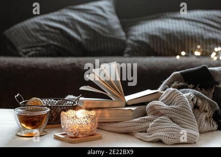 Still life with a cup of tea, books and a burning candle in a beautiful candlestick. Home comfort concept. Stock Photo