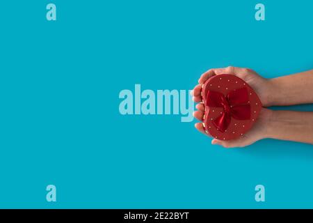 Woman hands holding heart shaped box on blue background Stock Photo