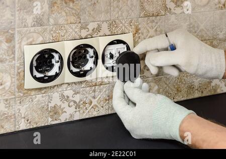 An electrician is installing switches and sockets on the wall. Stock Photo