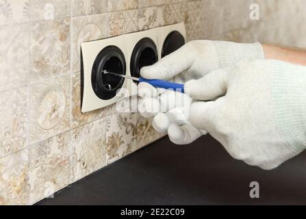 An electrician is installing switches and sockets on the wall. Stock Photo