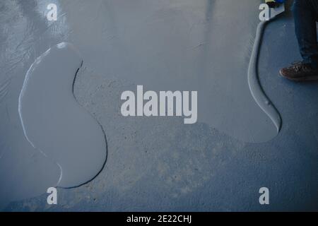 The worker applies gray epoxy resin to the new floor Stock Photo