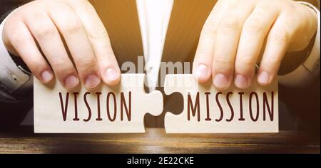 Businessman connects wooden puzzles with the words Vision Mission. Concept for business ideas and goals. Strategy development. Planning and action pla Stock Photo