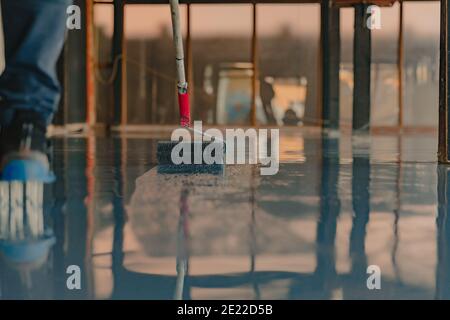 The worker applies gray epoxy resin to the new floor Stock Photo