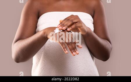 Skin Nutrition. Unrecognizable Black Woman Applying Moisturizing Body Lotion On Hands Stock Photo