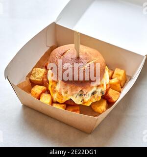 fresh tasty burger with beef, cheese and fried potatoes in paper take away box Stock Photo