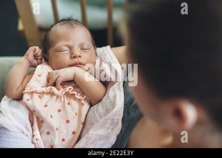 Upper view photo of a caucasian mother holding and looking at her newborn baby while she is sleeping Stock Photo