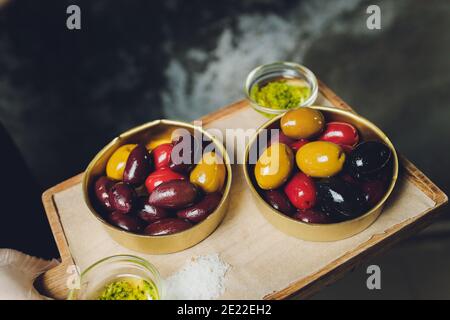 Variety of black and green olives and olive oil in bowls on white background close up Stock Photo