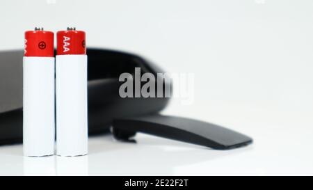 Black TV remote control with AAA alkaline batteries on a white background. Battery replacement, spare parts. Close up of an empty battery compartment Stock Photo