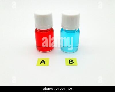 Stockholm, Sweden - January 11, 2021: Which treatment, medicine or vaccine would you choose? Two vials with red and blue liquid in them with the lette Stock Photo