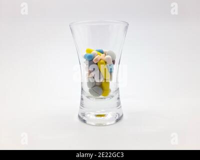 Stockholm, Sweden - January 11, 2021: A cocktail of pills in a shot glass. Different pills in many colors. Could use to symbolize addiction or overpre Stock Photo