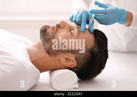Plastic surgeon injecting hyaluronic acid in man forehead Stock Photo