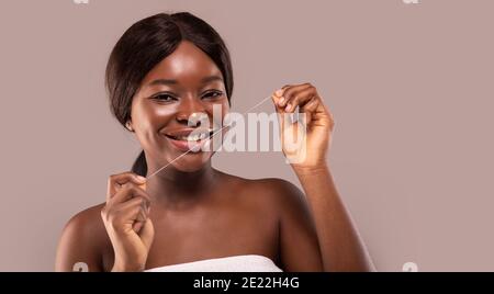 Oral Hygiene. Attractive African Woman Using Dental Floss And Smiling At Camera Stock Photo