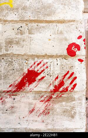 Grafiti on breeze block stone wall. Two red handprints on wall. Red hands with fingers all pointing unnaturally straight ahead. Stock Photo