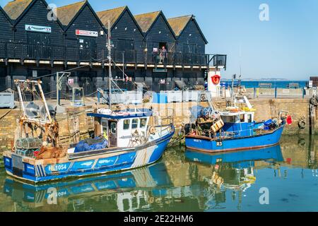 Fishing boats moored at Whitstable harbour on a sunny summer day with clear blue sky overhead. These fishing boats are used for oyster and shell fish. Stock Photo