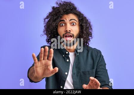 alarming scared panicking man is gesturing stop, afraid of something. arabic young male with long curly hair afraid and terrified with fear expression Stock Photo