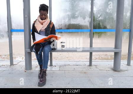 university female african student studying her lecture notes while is waiting for a bus on campus. college life concept. Stock Photo