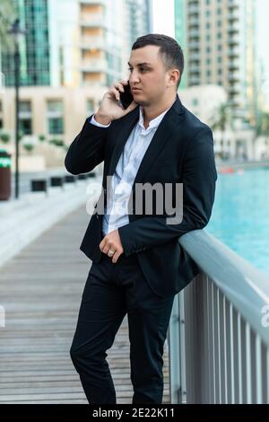 Young businessman in formal wear talking on mobile phone while walking in the city Stock Photo