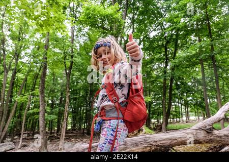 portrait from downwards angle of girl giving thumbs up while hiking Stock Photo