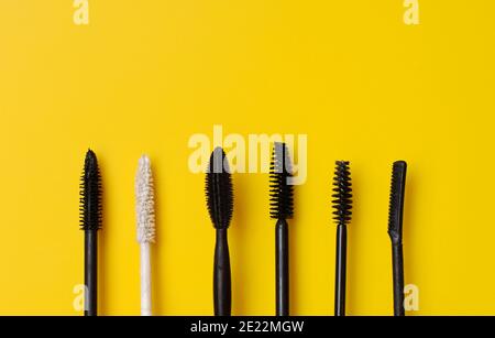 Various types of mascara wands on yellow surface Stock Photo