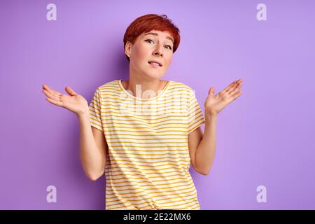 woman shrugging, i don't know. woman is misunderstanding , have doubts isolated on purple Stock Photo