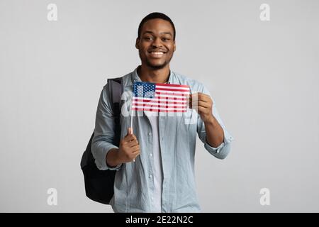 Positive black guy with backpack holding american flag Stock Photo