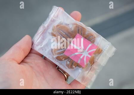 Momiji manjū, maple leaf shaped cake, in its packet, held in a woman's hand. Itsukushima (Miyajima), Japan Stock Photo