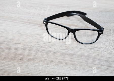 Glasses in black frames on a wooden table. Home Stock Photo